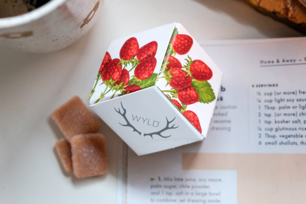 a carton of strawberry wyld edibles on a white background with 3 wyld gummies bar by the side