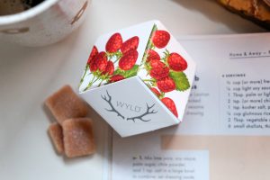a carton of strawberry wyld edibles on a white background with 3 wyld gummies bar by the side