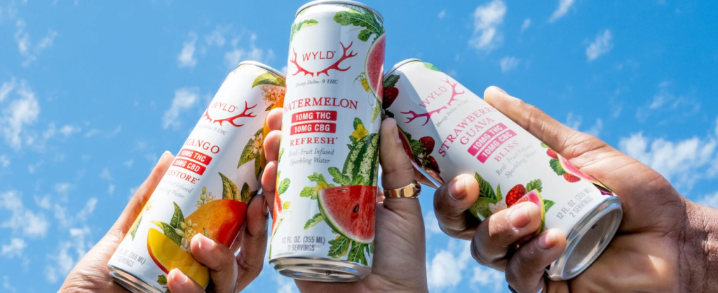 three bottle of wyld sparkling water held high in the air with a clear blue sky background