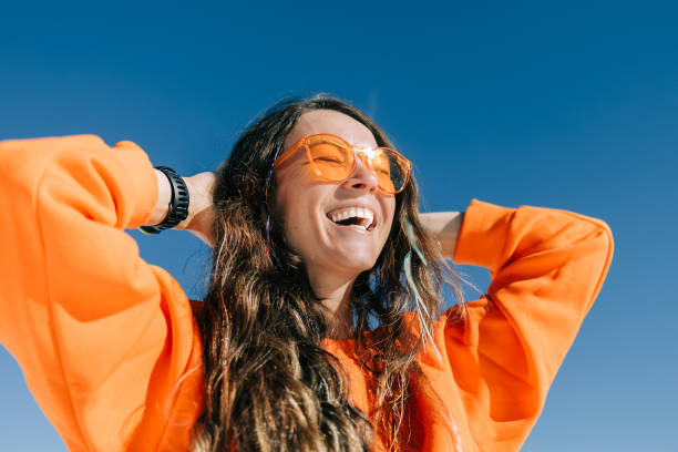 Cheerful woman in sunglasses embraces the sunshine surrounded by snowy mountains on sunny day after having wyld cbn gummies